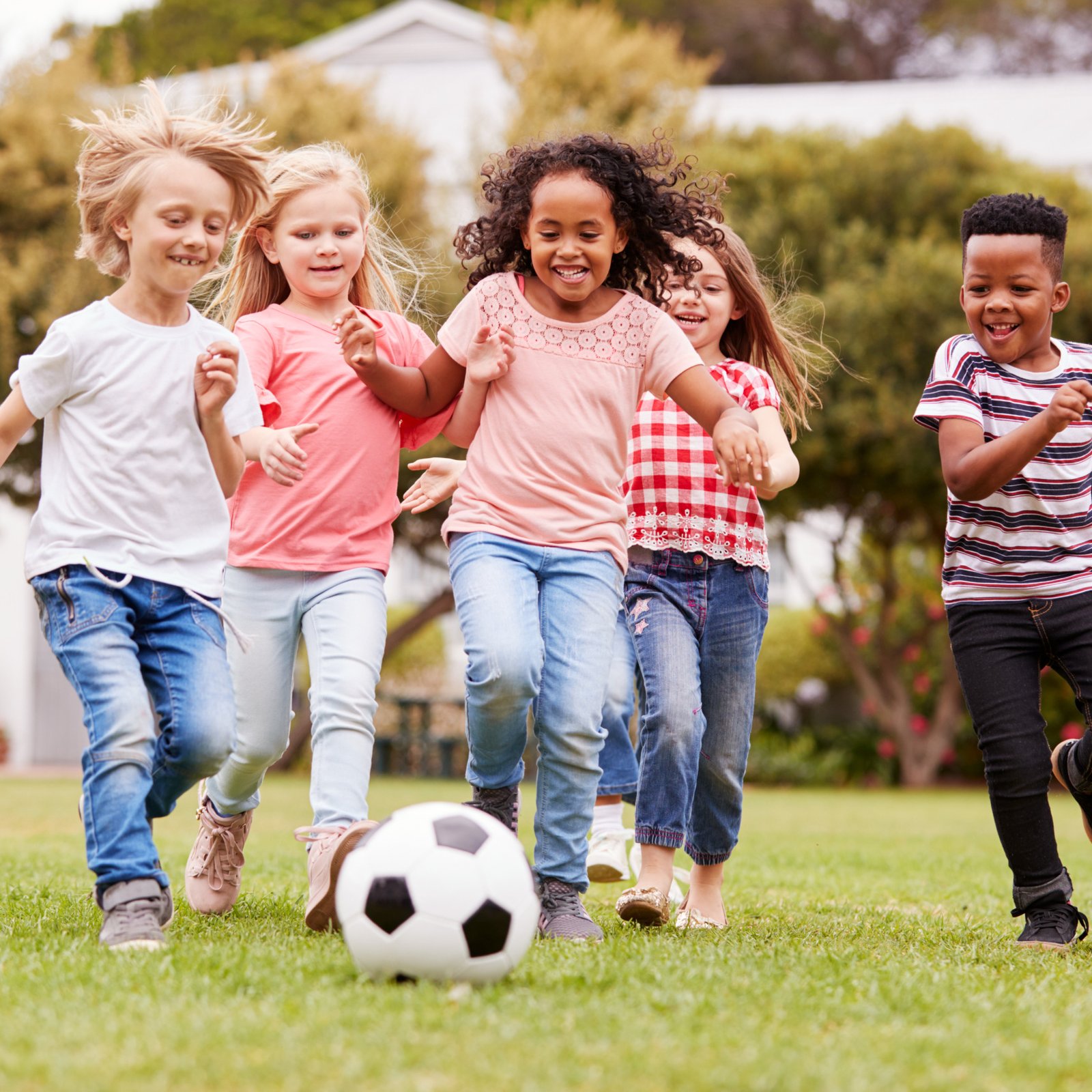Group Of Children Playing Football With Friends In Park